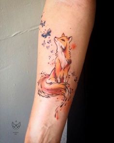 a fox tattoo on the arm with watercolor paint splatters and stars around it