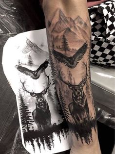 a man with a tattoo on his arm has an eagle and deer in the mountains