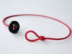 a red string with a black button on it sitting next to a white table top