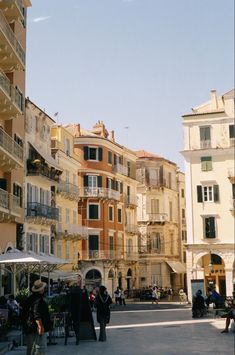 people are walking around in an open area with many balconies on the buildings