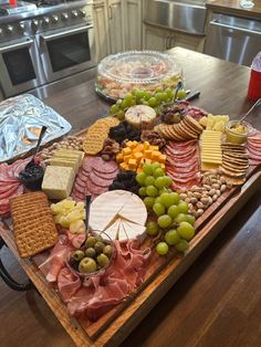 a wooden platter filled with assorted meats and cheeses on top of a table