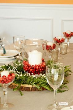 the table is set with candles, greenery and pomegranates on it