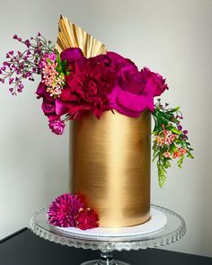 a gold cake with pink flowers on top