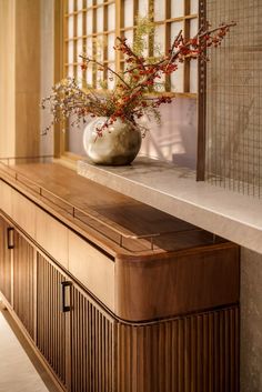 a vase filled with flowers sitting on top of a wooden cabinet