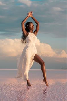 a woman in a white dress is dancing on the beach