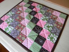 a pink and green patchwork quilt sitting on top of a table