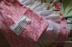 three baby swaddles laying next to each other on top of a bed covered in pink and green fabric