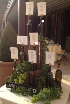 there is a table with wine bottles on it and place cards attached to the bottle