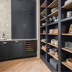 a kitchen with black cabinets and wooden shelves filled with dishes, wine glasses and other items