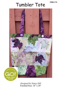 a purple and green tote bag sitting on top of a wooden chair with the words tumbler tote