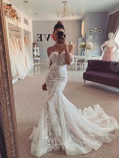 a woman taking a selfie in front of a mirror wearing a white wedding dress