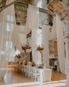 an indoor wedding setup with white drapes and flowers