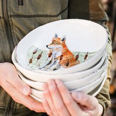 a person holding a stack of plates with a fox on it