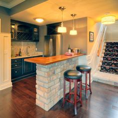 a kitchen with two stools next to a bar