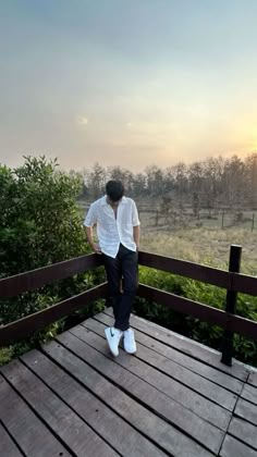 a person standing on a wooden deck looking at the grass and trees in the distance