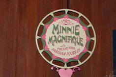 a sign on the side of a wooden door that says minnie's magnificent parisian poodles