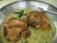 two pieces of meat on top of some green sauce in a pan with a fork