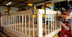 a man working on a wooden railing in a room filled with construction supplies and tools