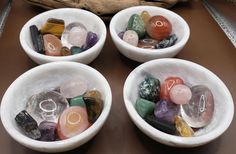 four white bowls filled with different colored rocks