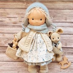 a doll and two stuffed animals are on a wooden surface with planks in the background