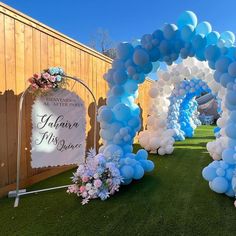 an arch with balloons and flowers on the grass