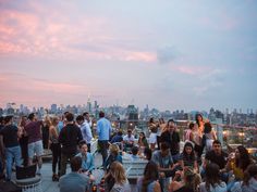 a group of people standing on top of a tall building next to a city skyline