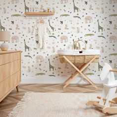 a baby's room with giraffe wallpaper and wooden furniture