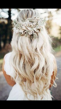 a woman with long blonde hair wearing a flowered headpiece in her hair is looking down at the ground