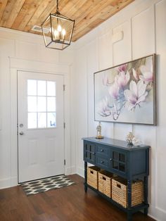 an entryway with a blue cabinet and two baskets on the floor, framed by a wood paneled ceiling