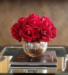 a glass table topped with a vase filled with red roses on top of a book