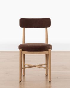 a wooden chair sitting on top of a hard wood floor next to a white wall