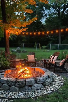 A cozy backyard setup with a stone fire pit, surrounded by chairs, string lights, and trees glowing in the evening light. Simple Fire Pit Area, Outdoor Patio With Fire Pit, Firepits Backyard, Fire Pit Garden, Outside Fire Pits, Cozy Gathering, Fire Pit Swings