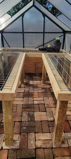 two wooden benches sitting in the middle of a brick floored area under a glass roof