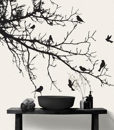 birds are sitting on the branches of a tree in front of a bowl and towel