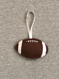 a brown and white football ornament hanging on a gray t - shirt,