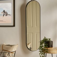 a mirror hanging on the wall next to a table with a potted plant in it