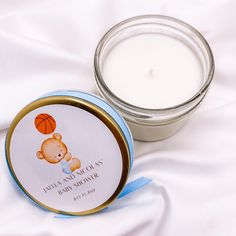 a small jar with a candle next to it on a white sheet that has a blue ribbon around it