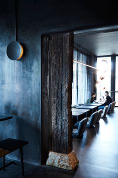 people are sitting at long tables in a dark room with large windows and wooden columns