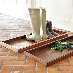 a pair of rain boots sitting on top of a wooden tray next to a plant