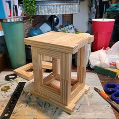 a wooden table with scissors and other crafting supplies on it's surface in front of a cluttered workbench