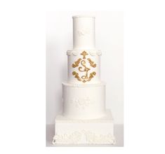 a three tiered white wedding cake with gold decorations