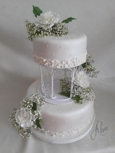 three tiered wedding cake with white flowers and greenery