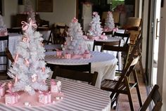 there are many small white trees on the tables in this dining room set up for a baby shower