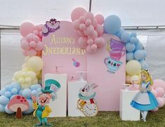 there are many balloons and decorations on the ground in front of a tent with alice's wonderland