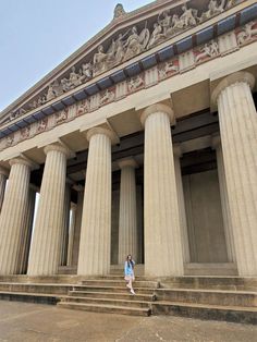 a woman standing in front of some large pillars