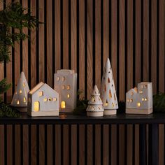 small white houses are lit up on a table