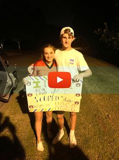 two people standing next to each other holding a sign