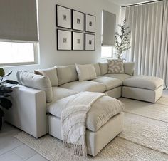 a living room with a large sectional couch in the center and pictures on the wall