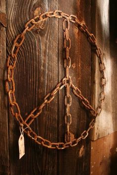 a peace sign made out of chains hanging on a wooden wall with a tag attached to it