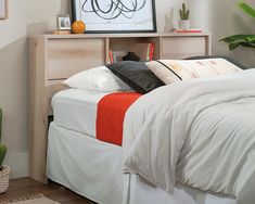 a bed with white sheets and orange pillows